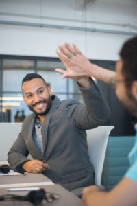Two male office workers giving each other a high five.