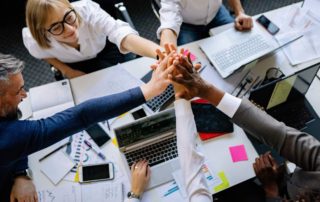 A team off office workers doing a team high five.
