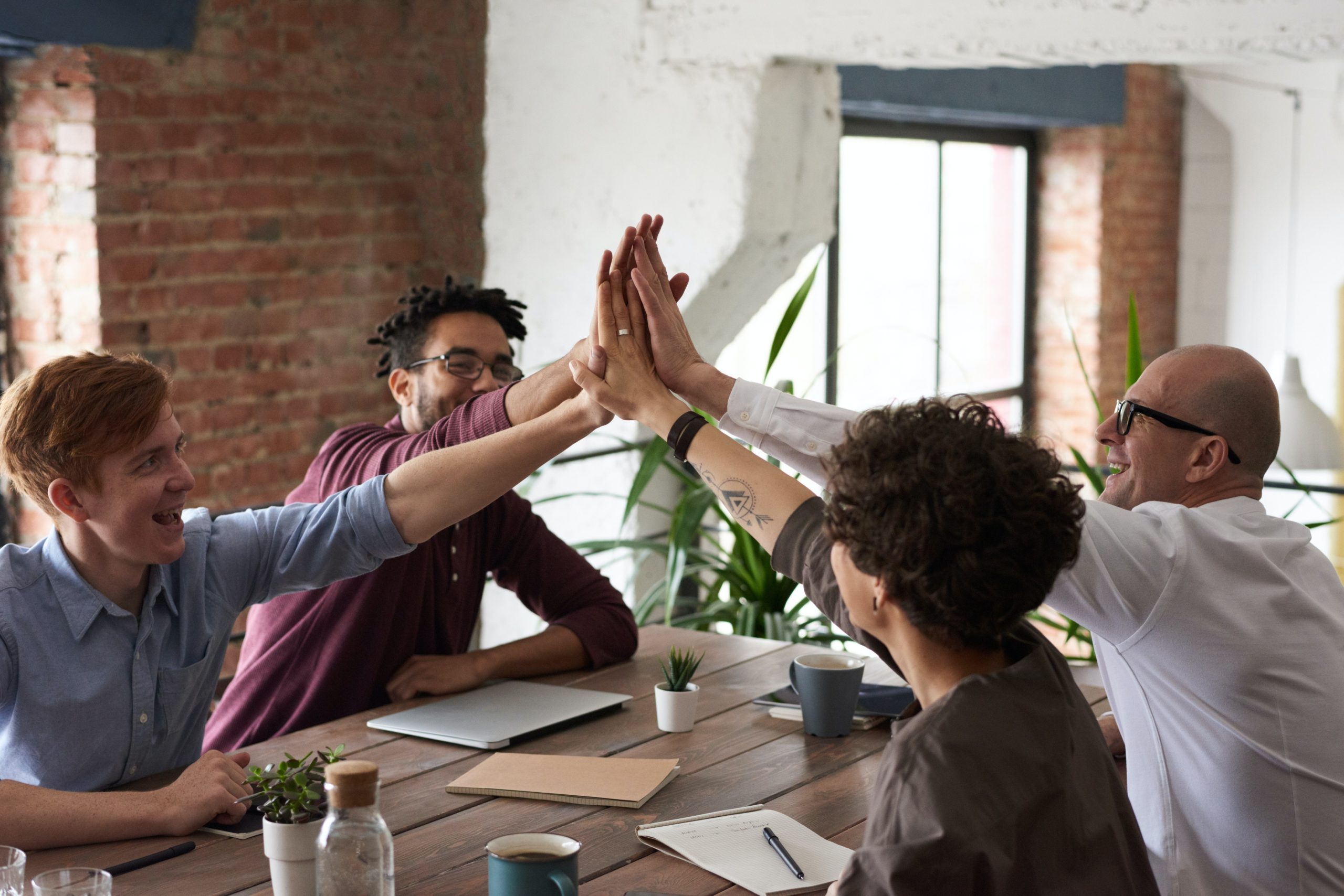 Working Genius Assessment Photo of a team of people giving each other a high five.