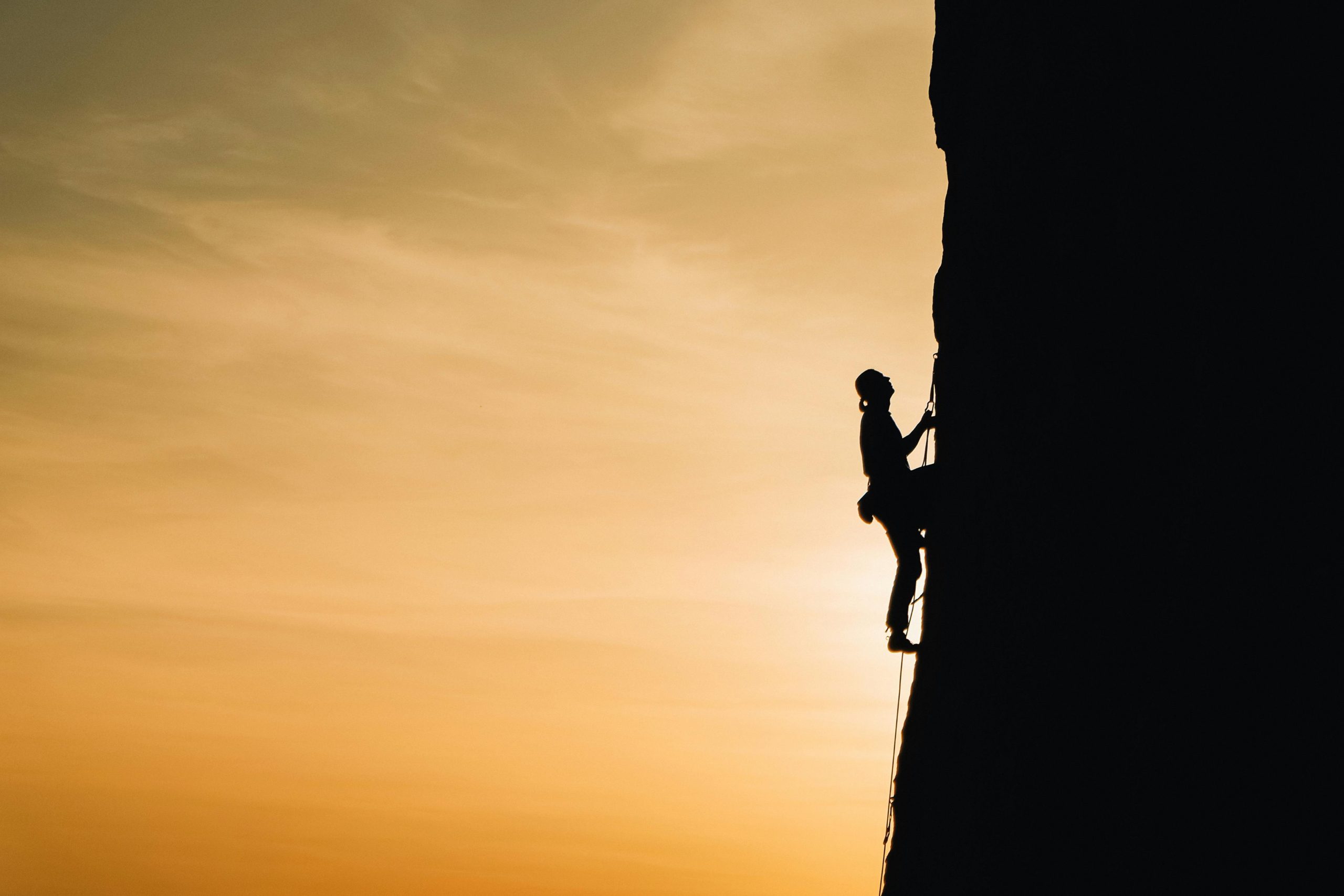 Person Rock Climbing to Rise to the top