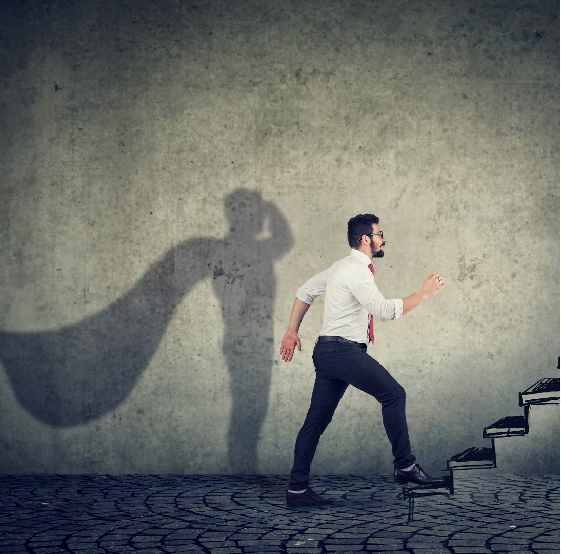 A business man going up the stairs with his shadow being reflected as a super hero