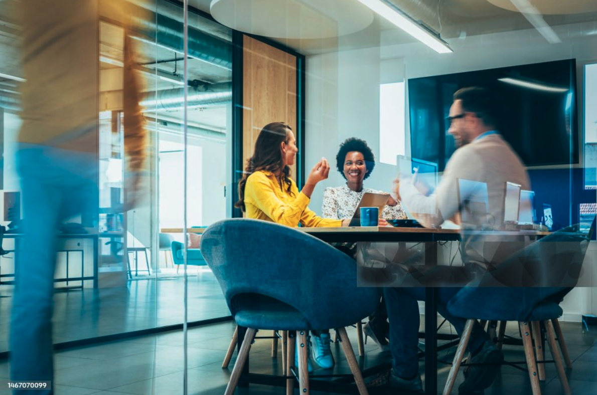 Three coworkers chatting amicably as they work on a project together.