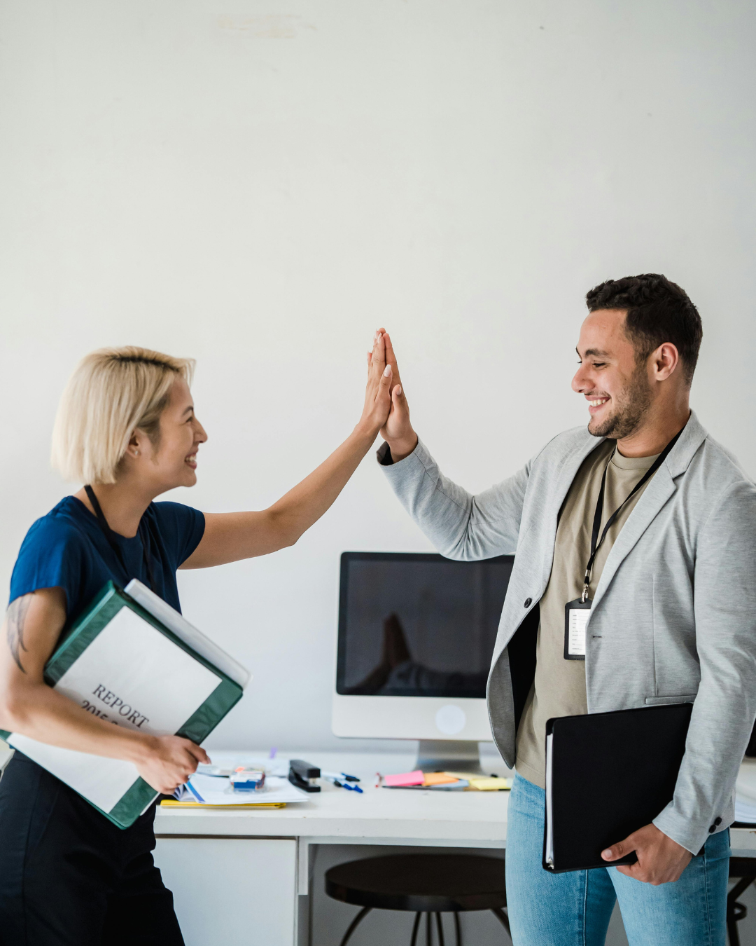Two businesspeople high-fiving in an office.